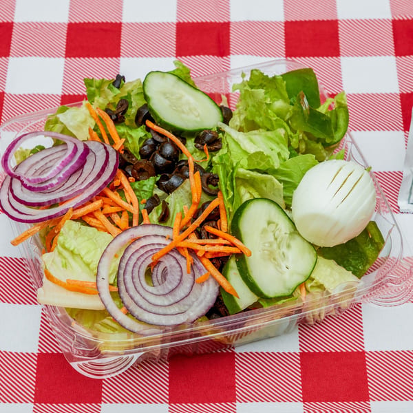 Fresh garden salad with lettuce, red onion, carrots, olives, cucumber, and hard-boiled egg.