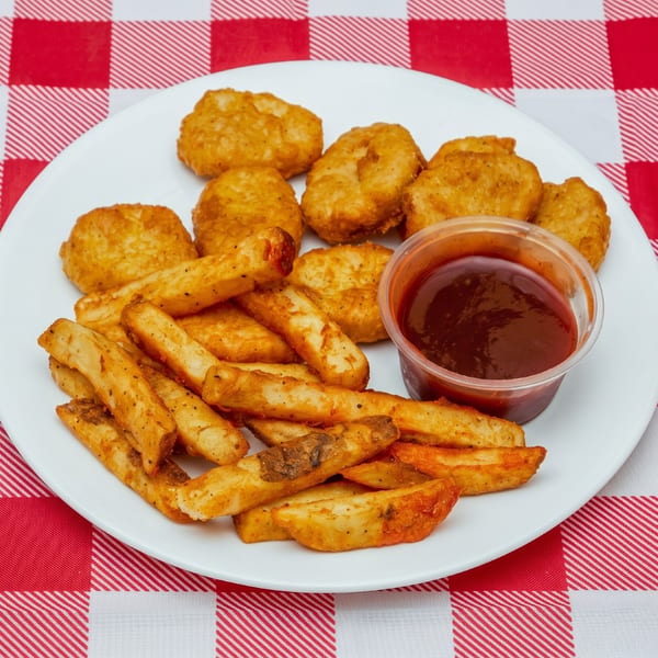 Chicken nuggets with seasoned fries and a side of BBQ sauce on a white plate over a red and white checkered tablecloth.