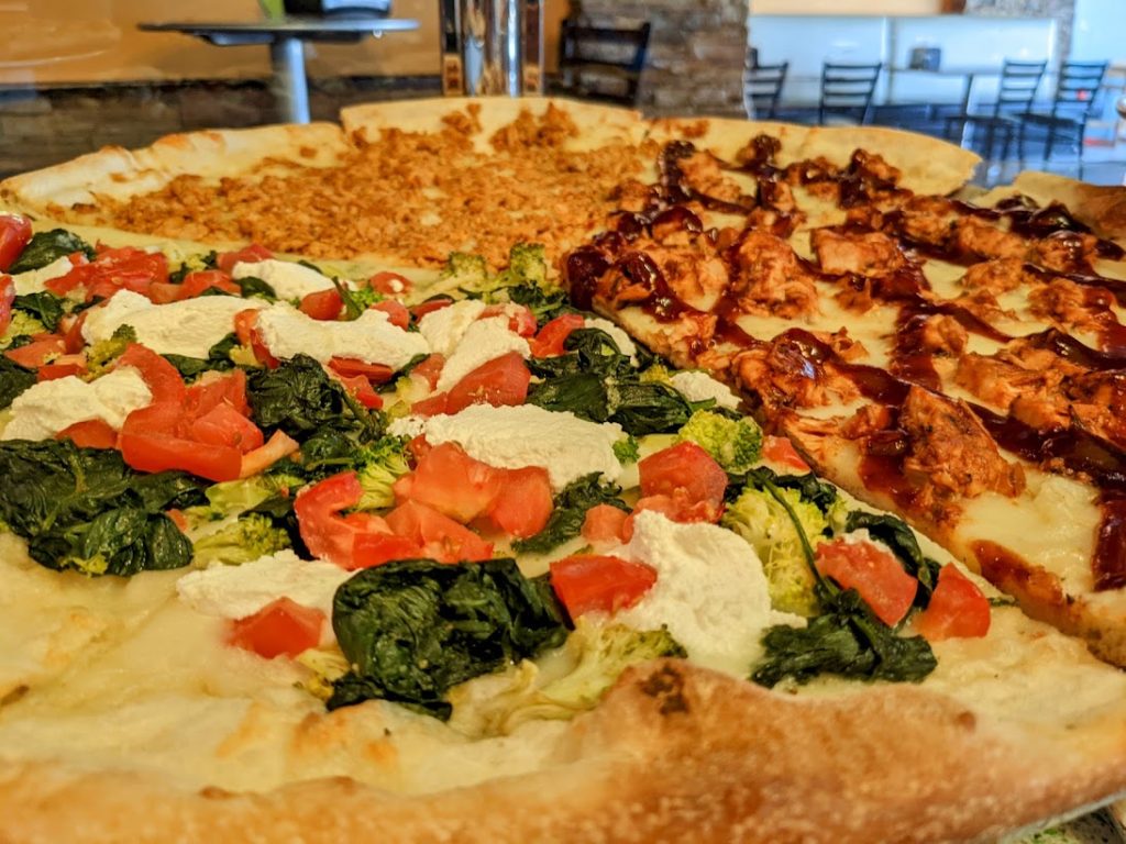 A pizza is sitting on a table with toppings on it.