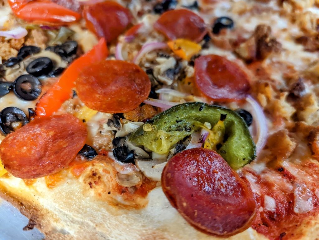 A close up of a pizza with pepperoni, olives, and onions.
