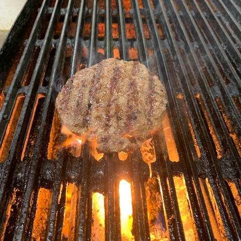A burger is being cooked on a grill.